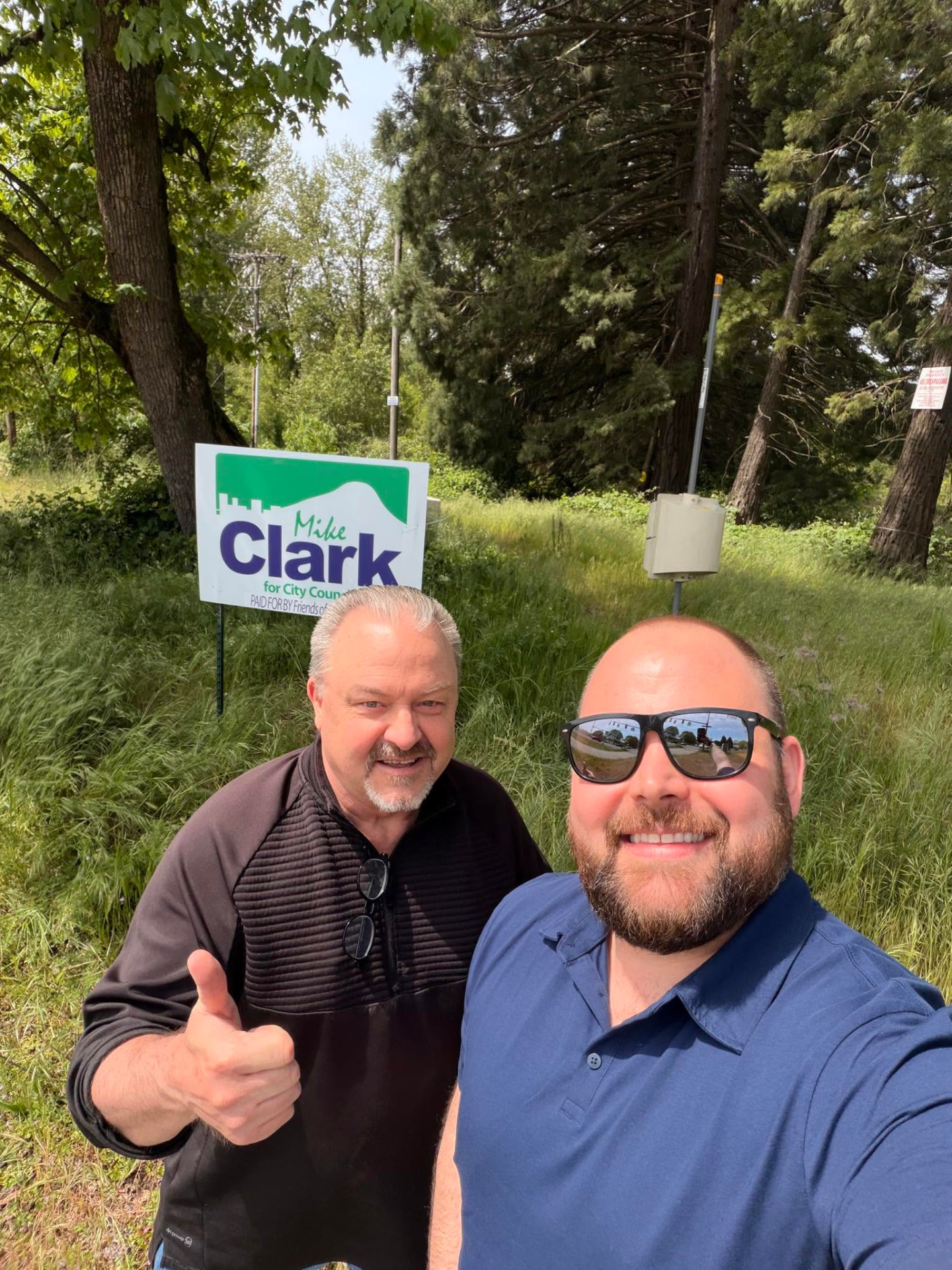 A supporter with Mike Clark next to a Clark for City Council yard sign